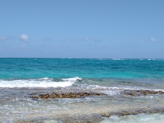 Beach with rocks that are touched by the waves of the sea foaming from the force of the shock, clear sand by the water, on a relaxing afternoon trip, together with a sunset, calm, everything is nature