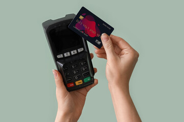 Woman with payment terminal and credit card on green background