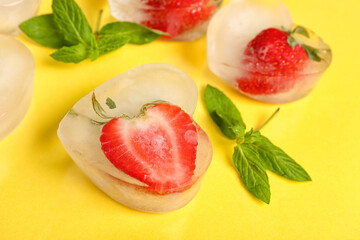 Fresh strawberry frozen in ice on yellow background
