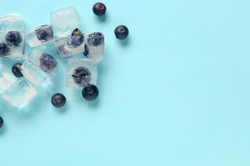 Ripe blueberry frozen in ice cubes and fresh berries on blue background