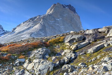 Photo of a majestic mountain landscape with rocks and lush green grass in Torres del Paine, Chile
