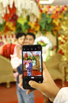 Person taking picture of a father and daughter with mobile phone camera 
