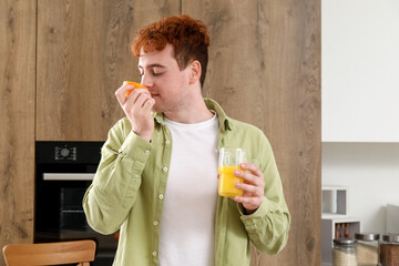Fototapeta premium Young man with glass of orange juice in kitchen