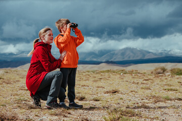 Boy tourist with binoculars and his mother in mountains - 613642013