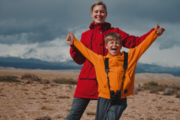 Happy boy tourist with binoculars and his mother in mountains