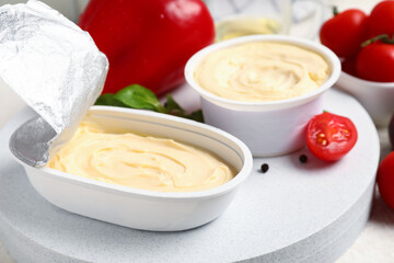 Plastic containers with tasty cream cheese on table
