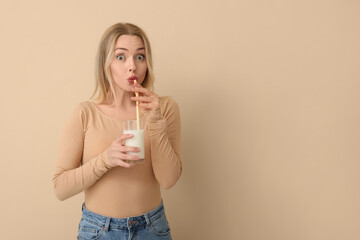 Naklejka premium Young woman drinking milk on beige background
