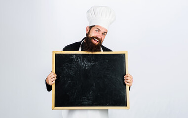 Smiling male chef with empty blackboard. Business lunch menu. Restaurant chef showing empty billboard with copy space for text. Male chef, cook or baker with blank poster for advertising healthy menu.