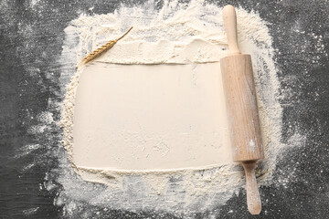 Wheat flour with rolling pin on grunge black background