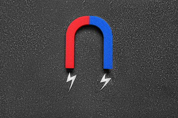 Paper lightnings with horseshoe shaped magnet on grunge black background