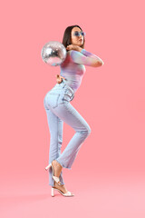 Fashionable beautiful woman in stylish sunglasses with disco ball on pink background