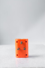 orange travel adapter on a white background, universal adapter on a white marble table