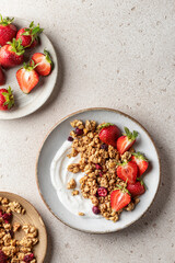 Healthy breakfast: fresh granola, muesli with yogurt, strawberry on beige textured background. Top view. Copy space