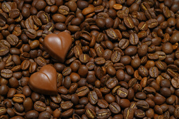 Tiny chocolate in heart shape on coffee beans. Close up. 