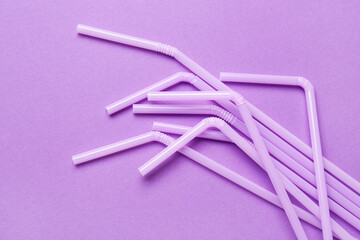 Lilac plastic straws on purple background