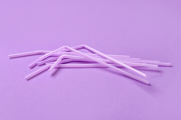 Lilac plastic straws on purple background