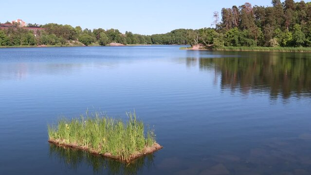 Small miniature green grass island. Sunny summer day at a Swedish lake. Natural lightning. Fr&ouml;sunda, Solna, Stockholm, Sweden, Europe.