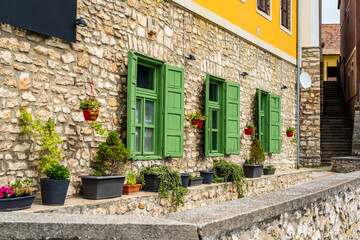 Fototapeta na wymiar Beautiful green jalousie windows of renovated old building with stone walls