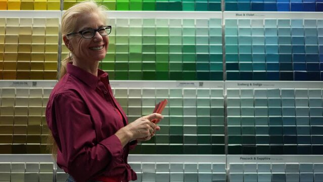 Portrait of woman looking at paint chips in a hardware store gives thumbs up. Concept of home remodeling shopping experience.