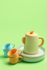 Obraz na płótnie Canvas Teapot with cups and plates for baby on green background