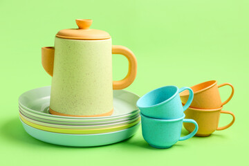 Teapot with cups and plates for baby on green background
