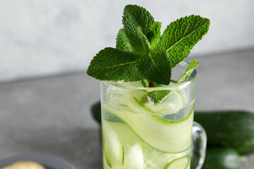 Glass of infused water with cucumber slices on grey table