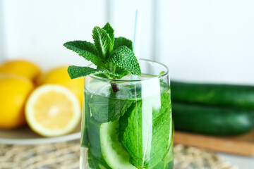 Glass of infused water with cucumber slices on blue background