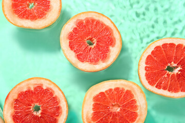 Slices of fresh grapefruit in water on turquoise background