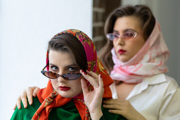 Two best friends, young girls dressed in retro vintage style with bright trendy make up of eighties...