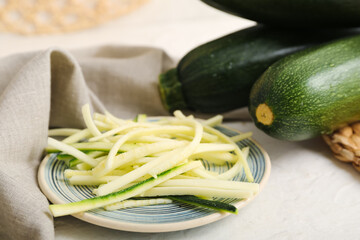 Fresh green zucchini and plate with slices on white background