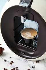 Modern capsule coffee maker with cup of delicious espresso on white table, closeup