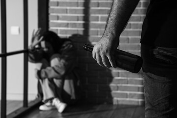 Drunk man with bottle of beer and his scared wife at home, closeup. Domestic violence concept