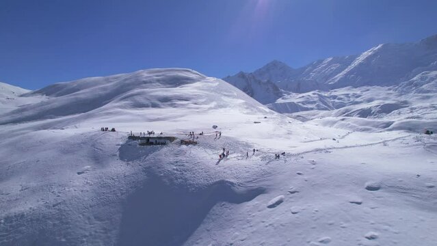 Aerial fly over groups of trekkers tourist on viewpoint in high altitude snowy Himalaya mountains on sunny day. Tilicho lake trekking route, Manang, Nepal