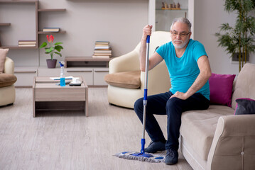 Old male contractor cleaning the house