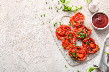Board with tasty grilled tomatoes and green onion on grey background