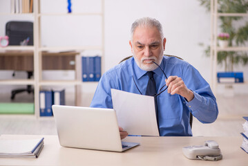 Old male employee working in the office