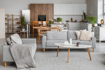 Interior of light open plan kitchen with grey sofas and coffee table