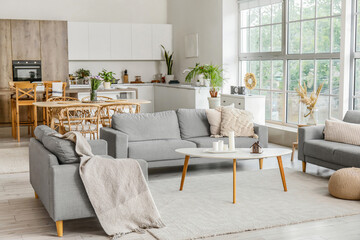 Interior of light open plan kitchen with grey sofas and coffee table