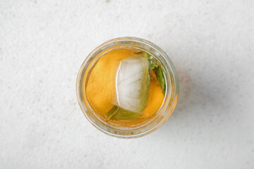 Glass of ice tea with lemon and mint on white background