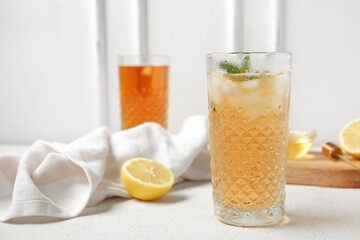 Glasses of ice tea and board with lemon on white background