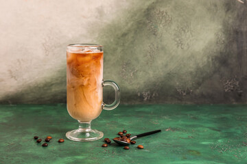 Glass cup of tasty ice coffee with milk on grunge background