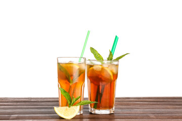 Glasses of ice tea with lemon and mint on wooden table against white background