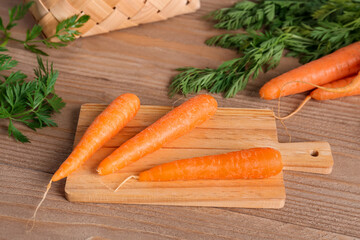 Board with fresh carrots on wooden table
