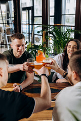 Happy group of friends drinking and clinking with beer and cocktails at brewery bar restaurant. Beverage life style concept with guys and girls having fun together