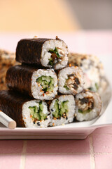 Plate with tasty maki rolls on table, closeup
