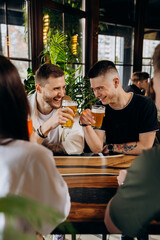 Happy group of friends drinking and clinking with beer and cocktails at brewery bar restaurant. Beverage life style concept with guys and girls having fun together