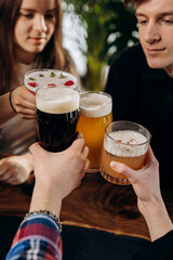 Friends hands toasting and having fun together drinking beer and cocktails at happy hour in pub restaurant . Social life style party time concept