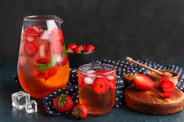 Glass and jug of infused water with strawberry on black background