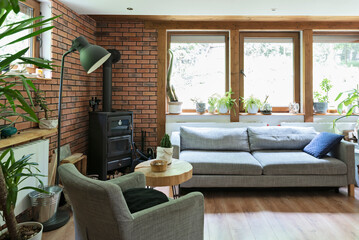 Rural cottage with cozy design, windows to the forest, fireplace, sofa, armchair and red brick...