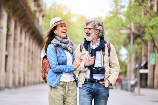 Happy older couple having fun walking outdoors in city. Retired people enjoying a sightseeing walk on street in spring. Mature couple relationships and vacations of pensioners.